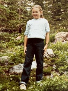 A young girl posing for a photo in the woods.