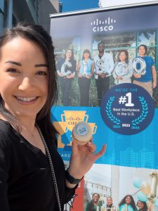 Kim holding Cisco cupcake in front of Great Place to Work signage.