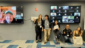 Cisco employees sitting and standing in front of TVs displaying video call of other Cisco employees.
