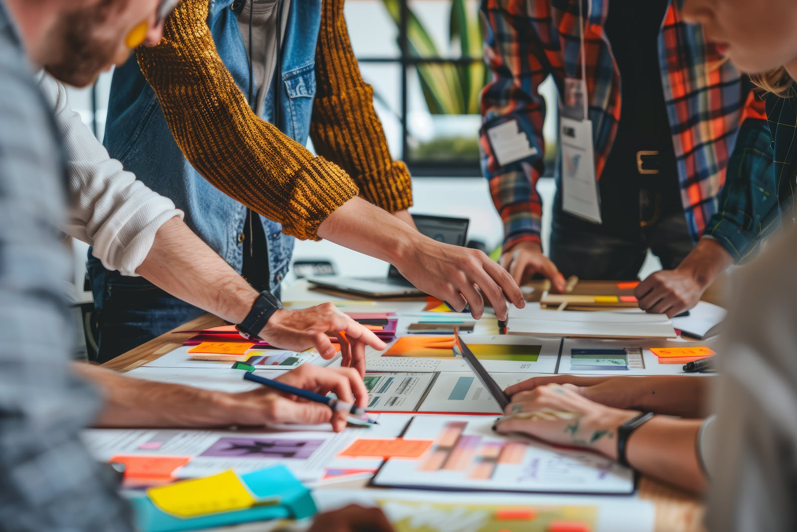 People working around a table but only seeing their arms and hands as they work together on a project