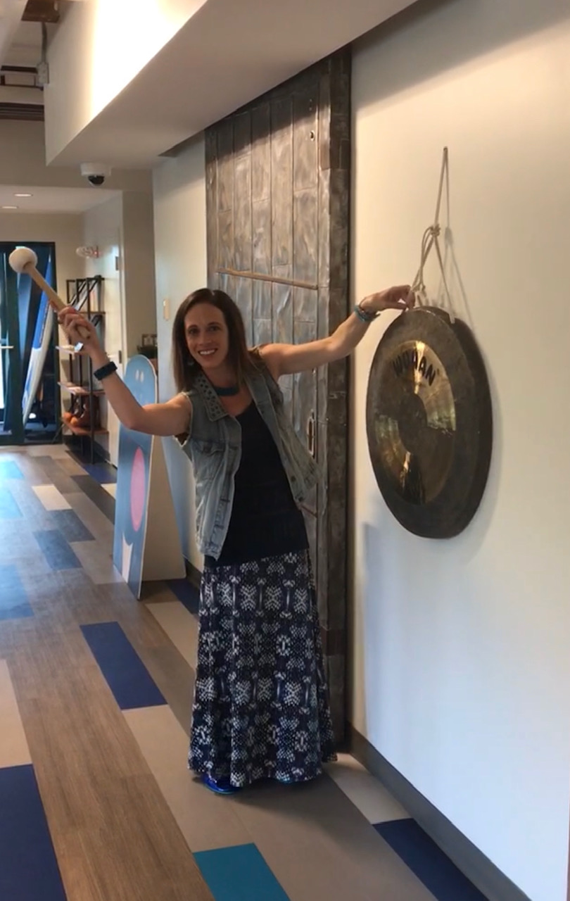 Sara poses with the infamous gong at Cisco Waltham before striking it!