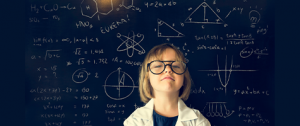 Little girl wearing glasses with Einstein drawings in the background