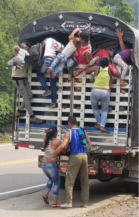 Refugees trying to hitch a ride on the back of a truck