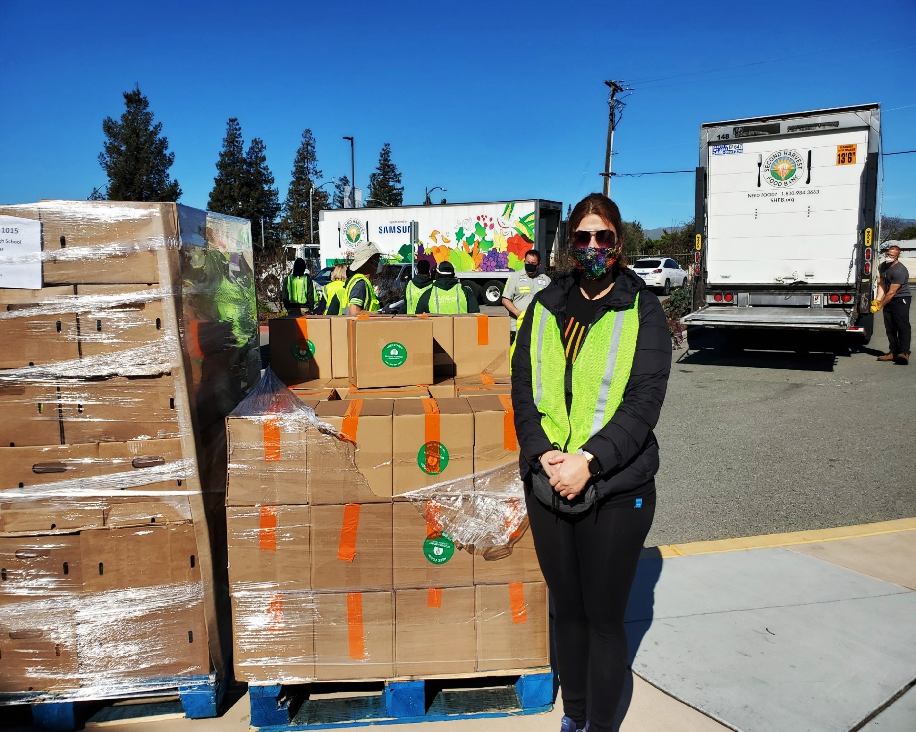 Pelin standing next to crates at a giveback event.