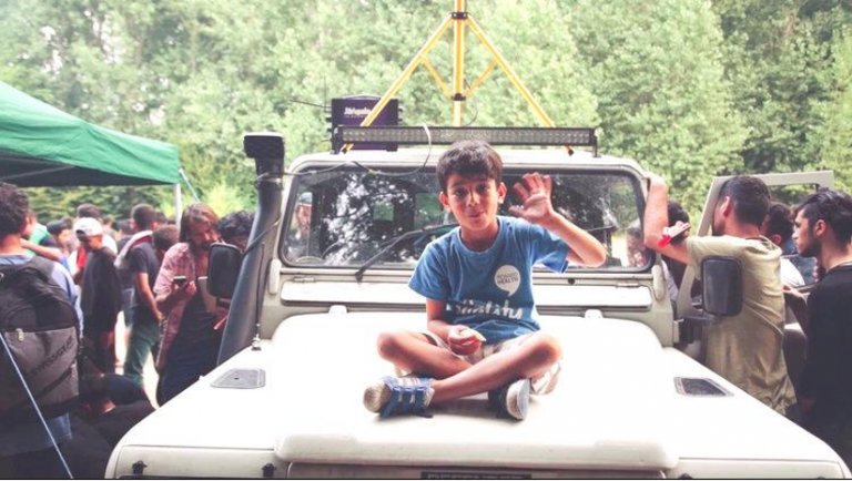 Boy sitting on hood of car