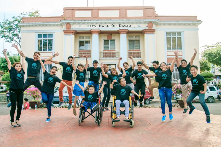 A group of people joyfully jumping in front of a building.