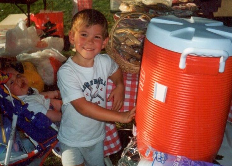 A young boy standing next to a water cooler
