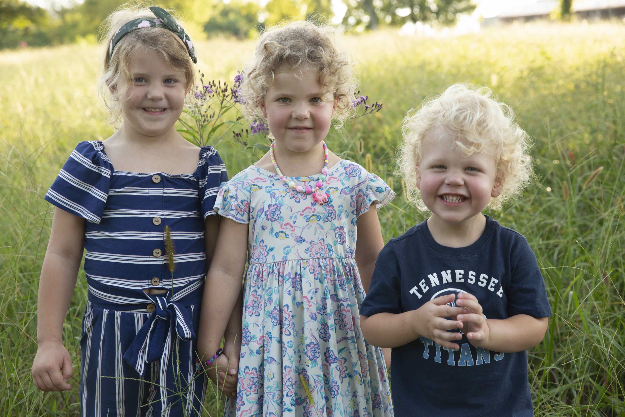 Audrey's three children posing in a field.