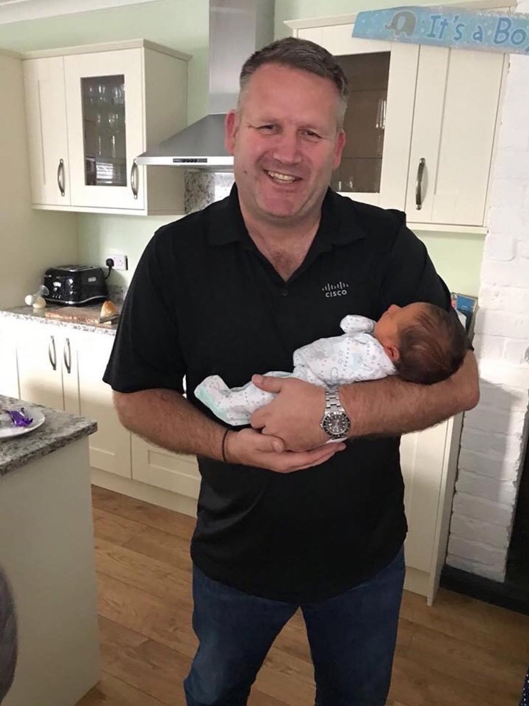 Gavin holding a baby in a Cisco tshirt.