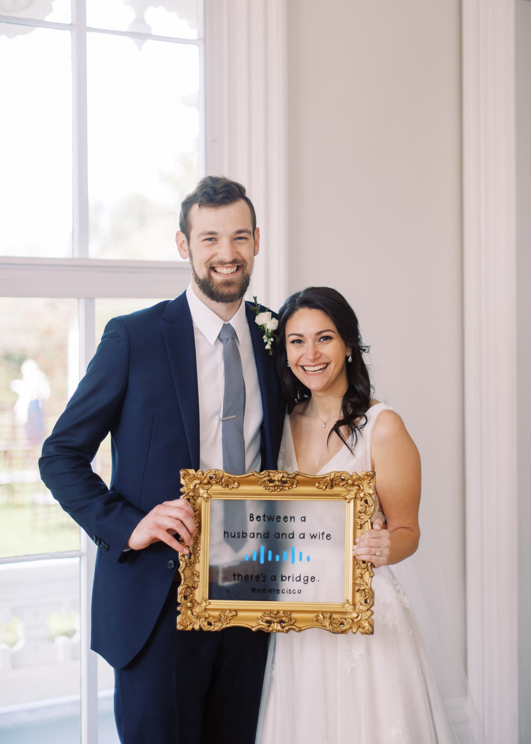 Anna and Paul at their wedding, holding up a Cisco sign. 