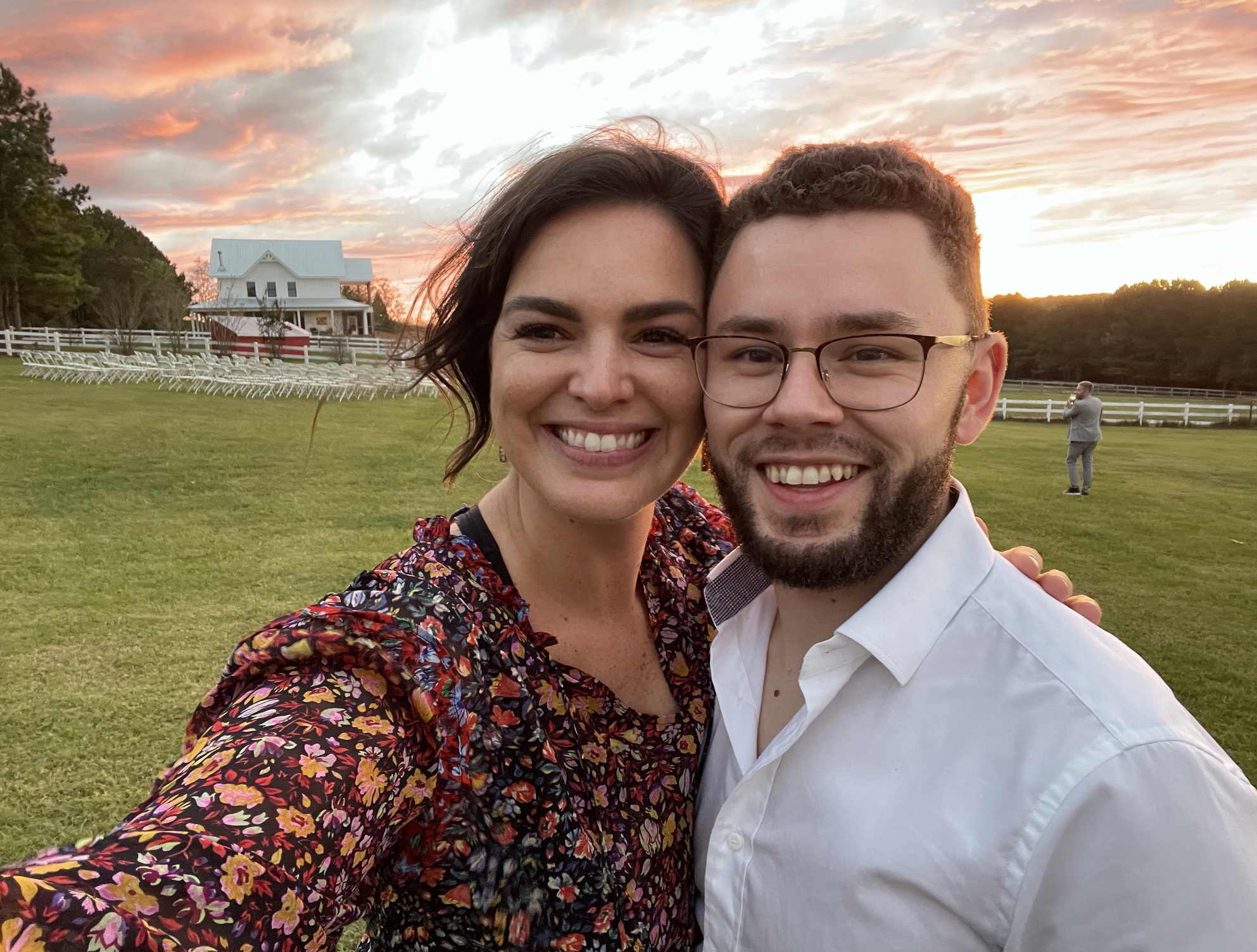 Chelsea and Chris take a selfie with a sunset behind them.