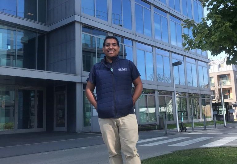 Emmanuel standing in front of office building, smiling.