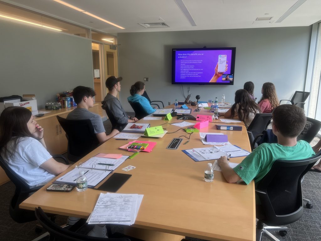 Students sitting around a table watching a presentation