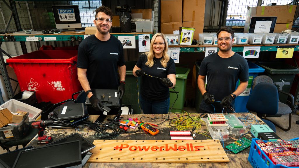Two men and a woman wearing black tshirts and working with electronics