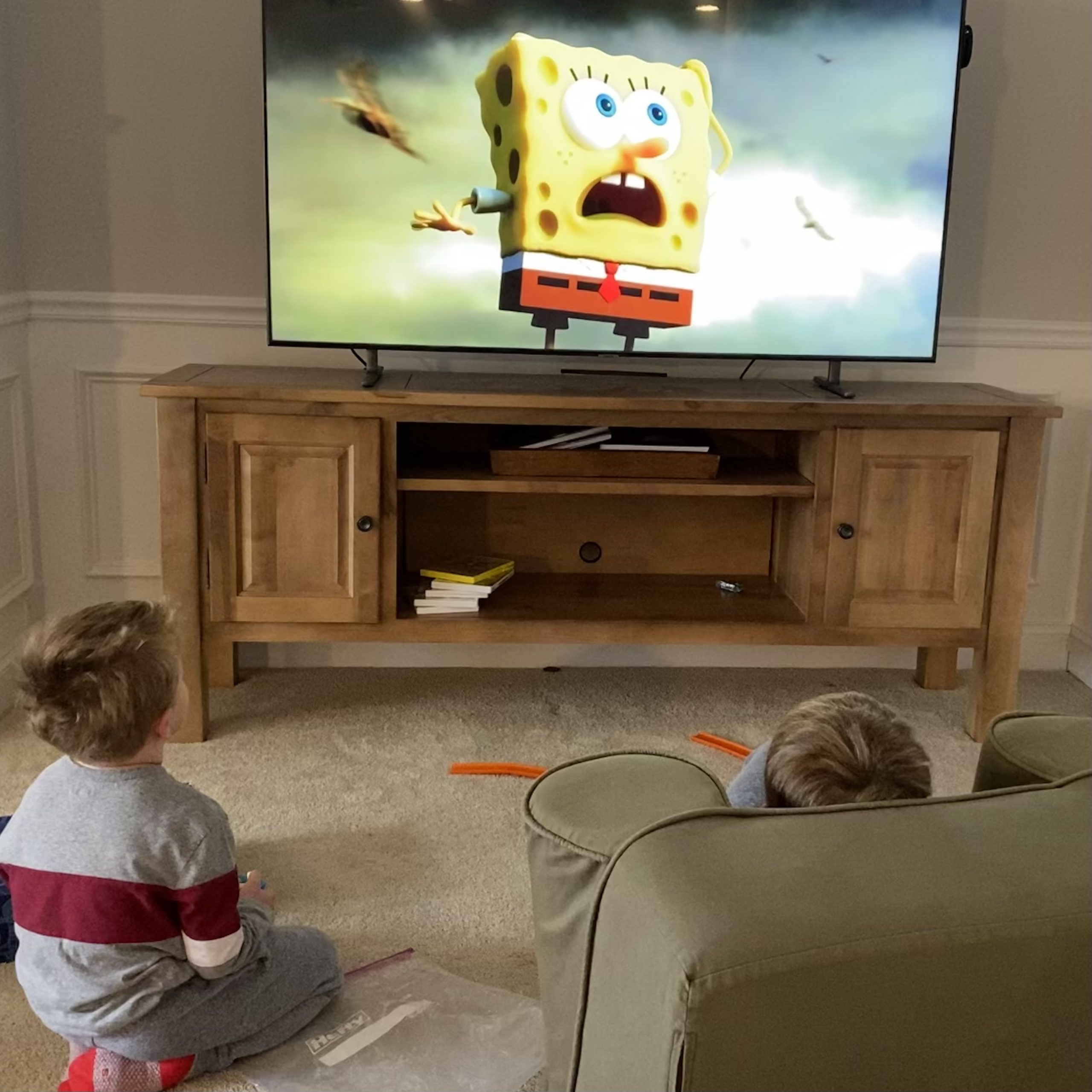 Two young boys sitting on the floor watching Spongebob Squarepants on TV. 
