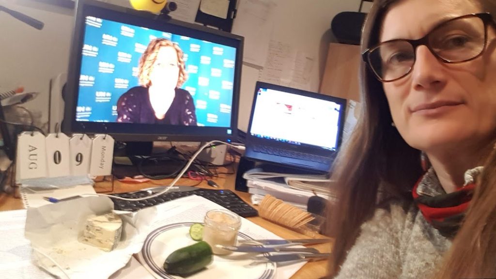 A woman with a plate of cheese in front of a computer screen