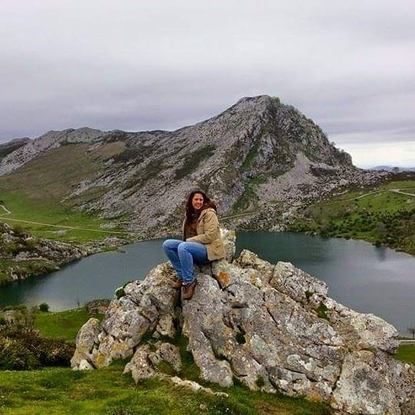 A woman sitting on some rocks in front of a lake.