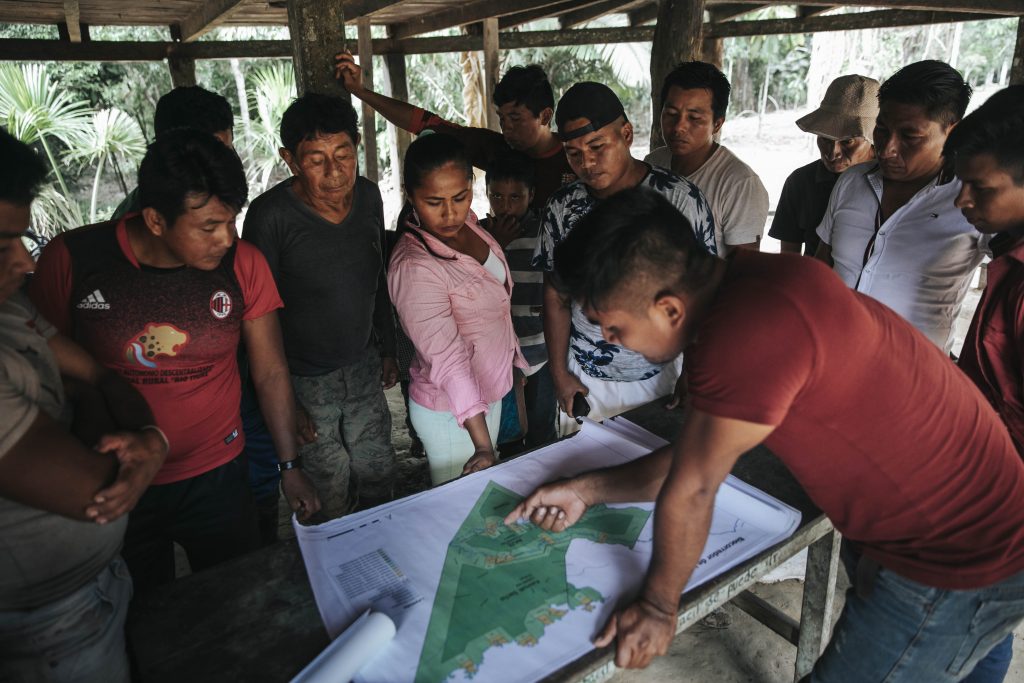 A group of people, gathering around a map
