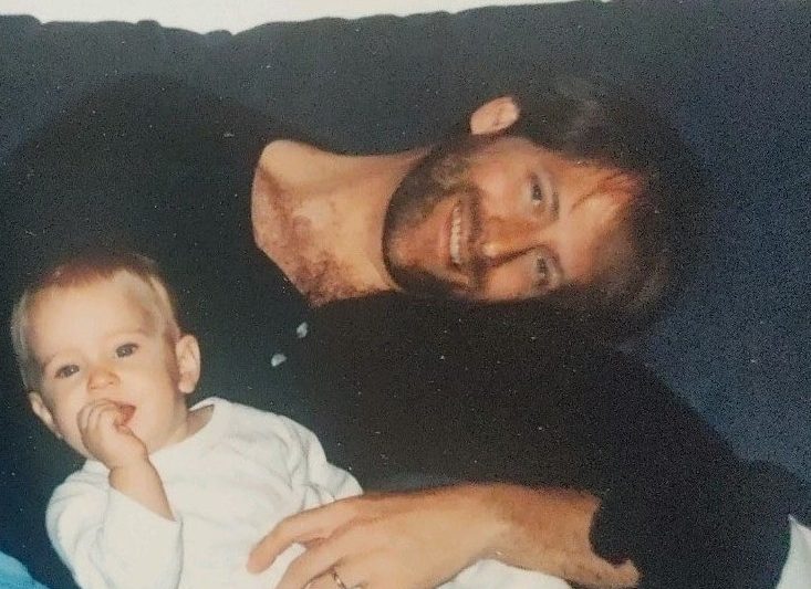 Alex as a baby on a couch with her father Logan.