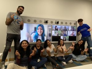 Cisco employees standing and sitting in front of video screens displaying other Cisco coworkers.