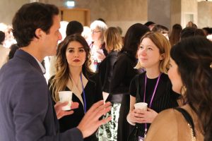 Three women having a discussion with a man at a networking event.