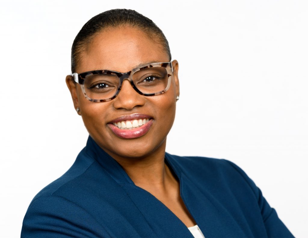 A woman wearing glasses and a blue blazer, smiling for the camera