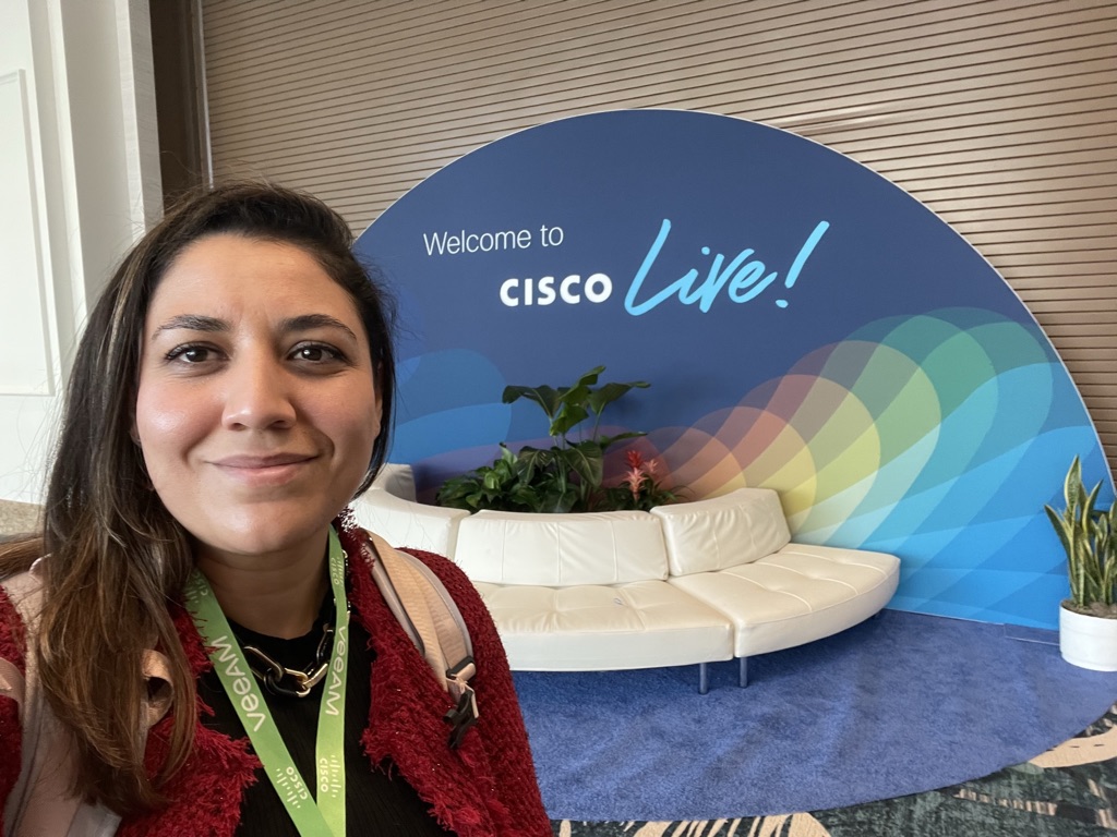 Carmen in front of a sign that reads, "Cisco Live!"
