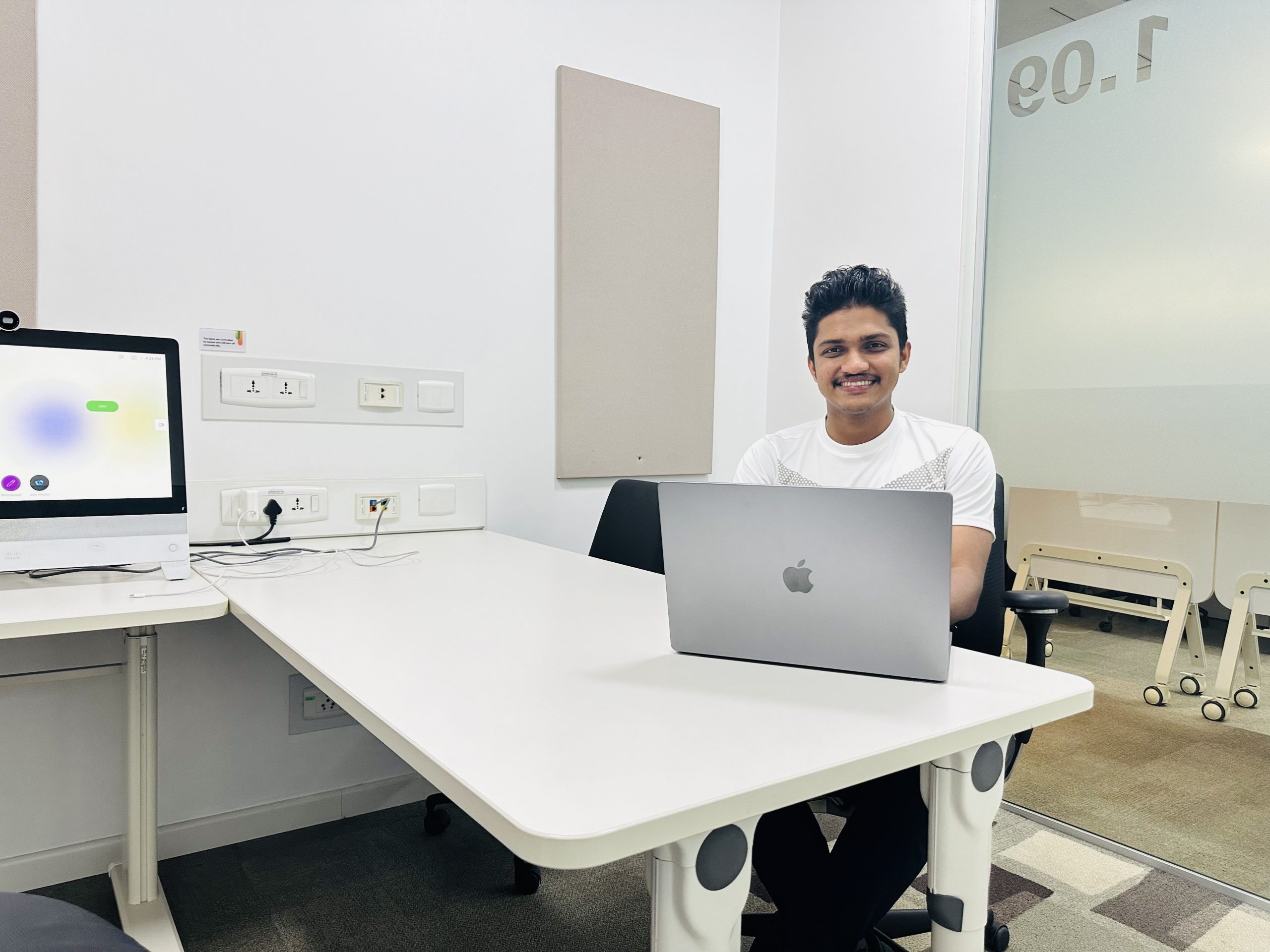 Najid smiling at the camera working on his MacBook Pro in a Cisco office