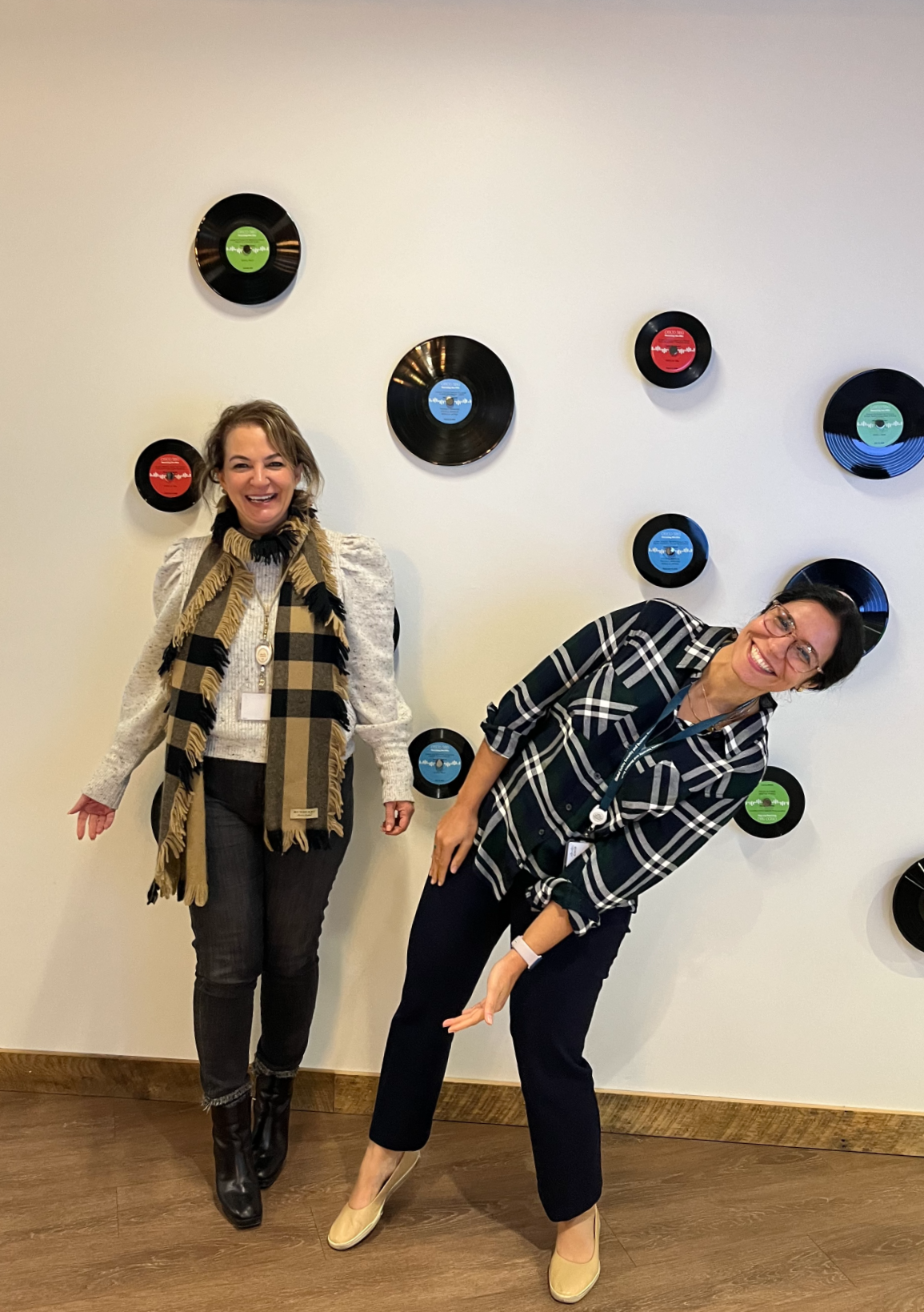 Niloo and her executive mentor playfully posing in front of white wall with records
