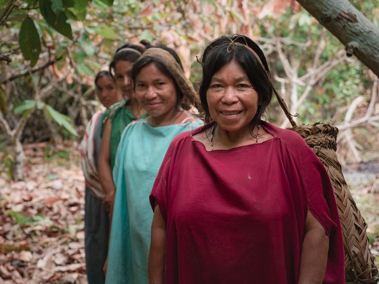 4 women standing in a forest setting in colorful clothing