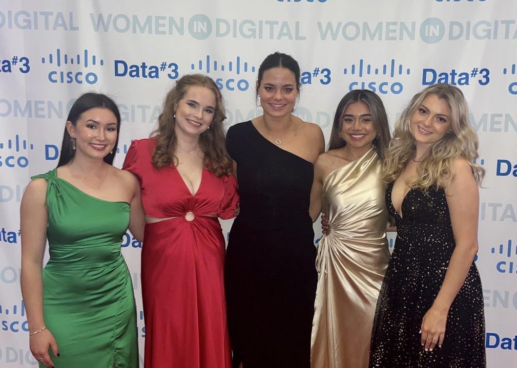 Beate Aftret and four other women in formal dresses posing in front of banner with Cisco and Data#3 logos on it.