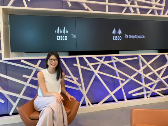 Mabel sits proudly in front of screens displaying the Cisco logo.