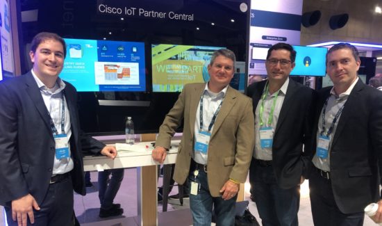 Andre and his colleagues stand in front of a Cisco IoT presentation.
