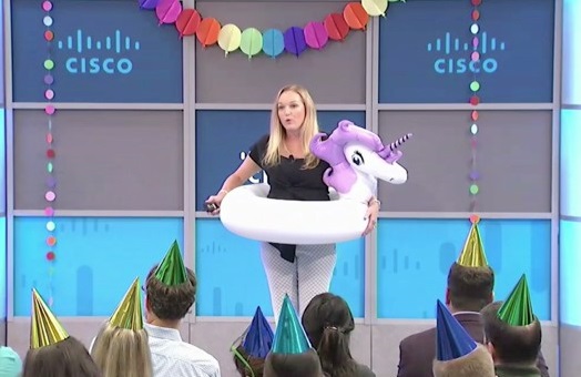 Erin standing inside an inflatable unicorn pool float while presenting at Cisco.