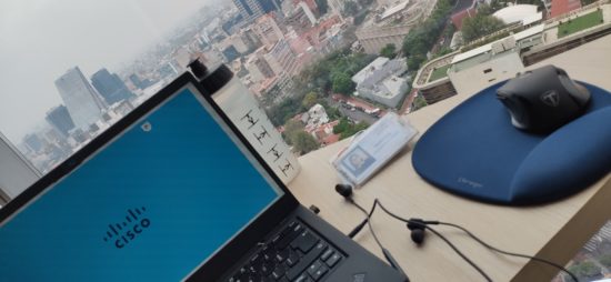 Yartiza's Cisco badge and laptop with a Cisco background on a desk overlooking Mexico City.