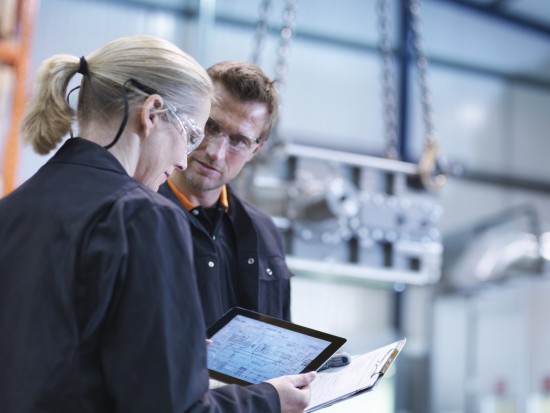 11 Nov 2013 --- Engineers inspect plans on digital tablet in engineering factory --- Image by © Monty Rakusen/Corbis