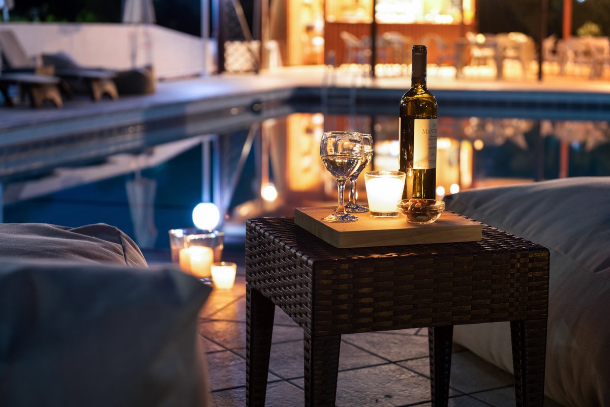 Wine bottle and glasses beside the pool by night