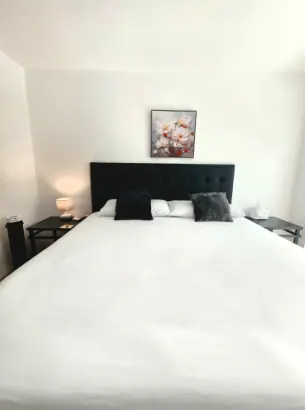 King bed with white linens and floral art above the headboard