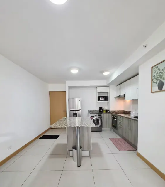Modern kitchen with island, stainless fridge, oven, and in-unit washer