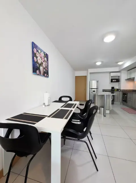 Dining table with black chairs looking into the open kitchen