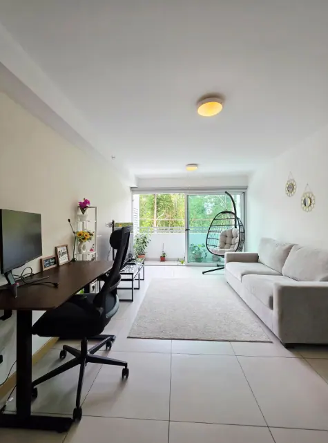 Open living room with sofa, workspace desk, and balcony beyond
