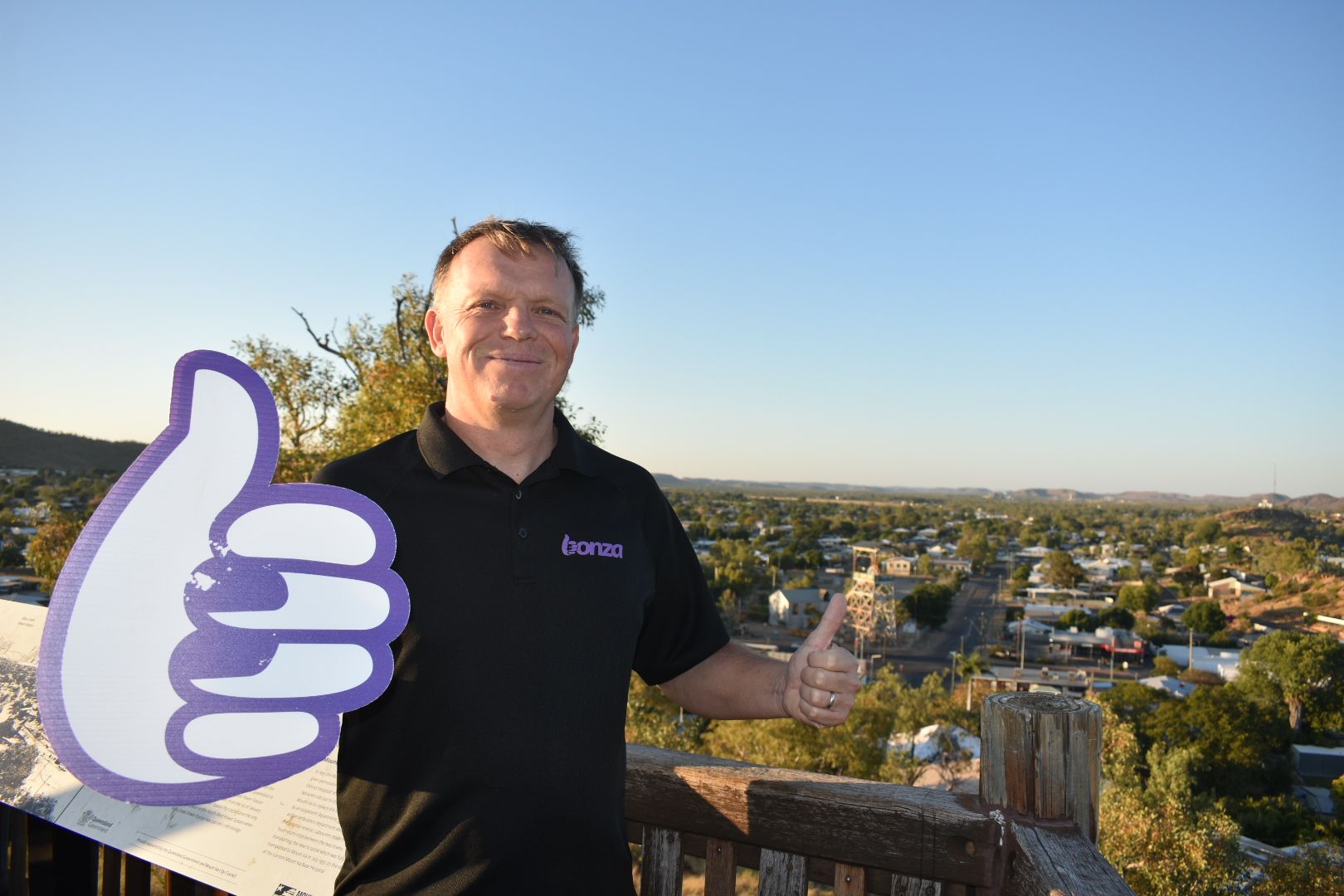 Tim Jordan, CEO of Bonza, shown in Mount Isa, Queensland, with a big purple thumbs up Bonza logo