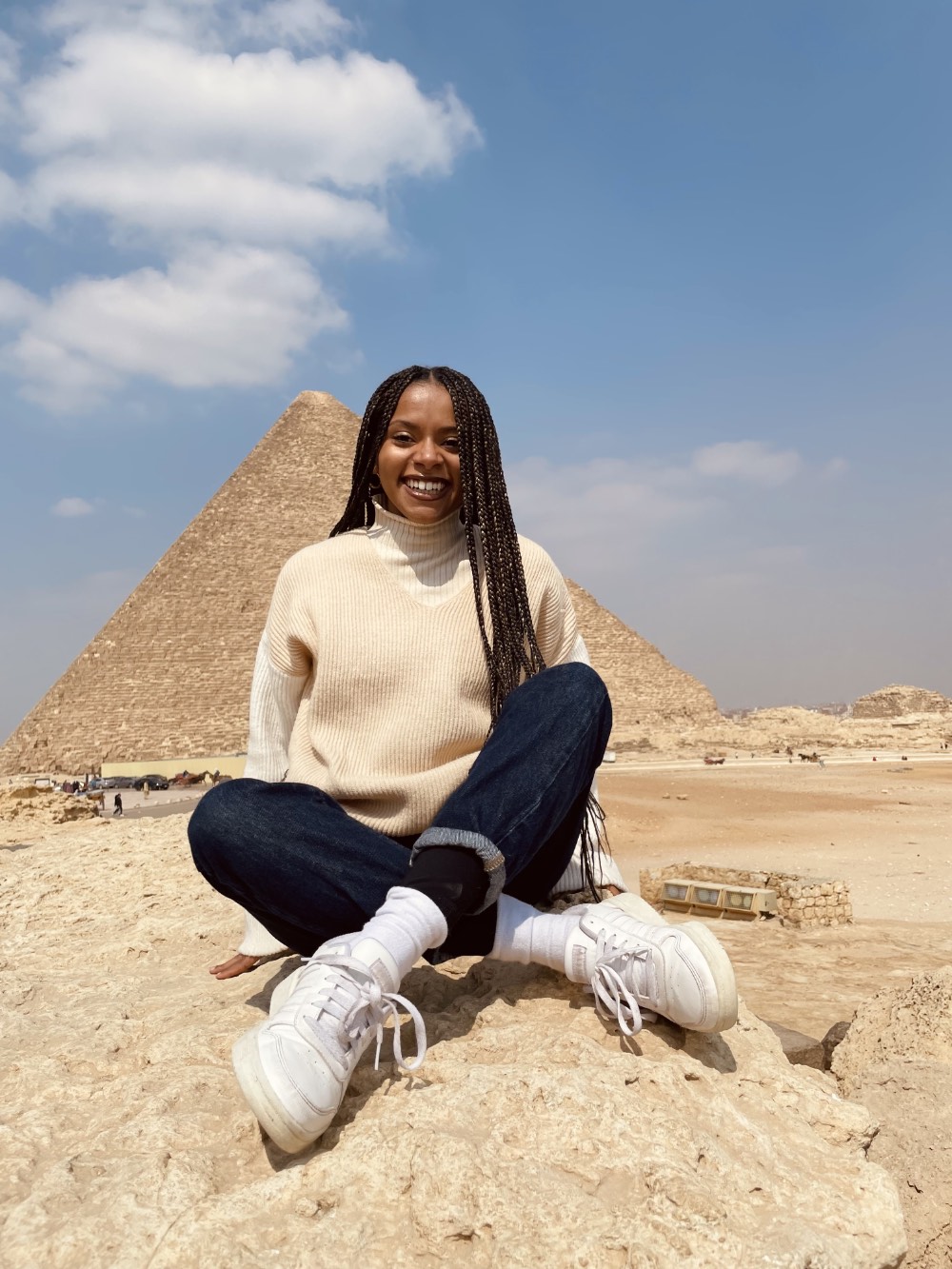 Tatyana sitting in front of the Great Pyramids of Giza during her senior year spring break with friends