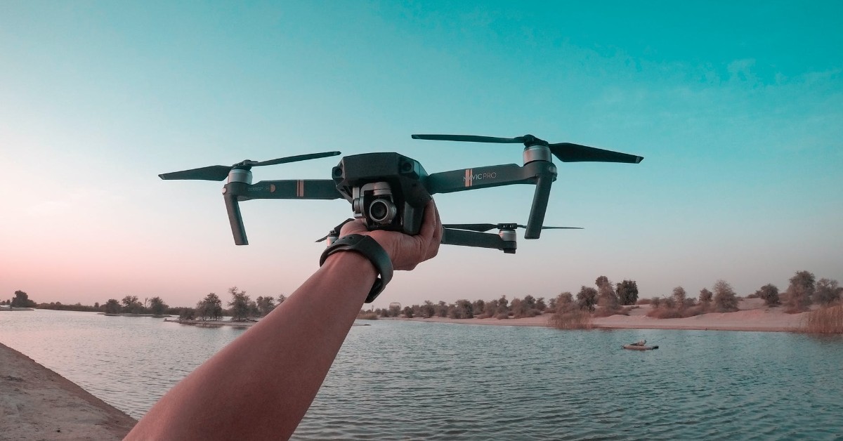 person holding drone in front of lake