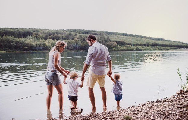 A couple plays with their children by a lake.