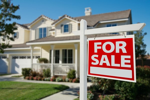 A “For Sale” sign is posted out in front of a single-family home with a freshly cut lawn. 