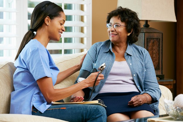 A nurse checking the blood pressure of a senior patient at home.