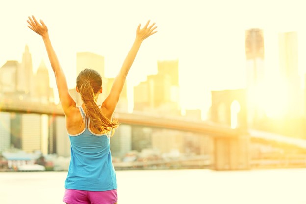 A jogger stops to celebrate the sun shining over a city.