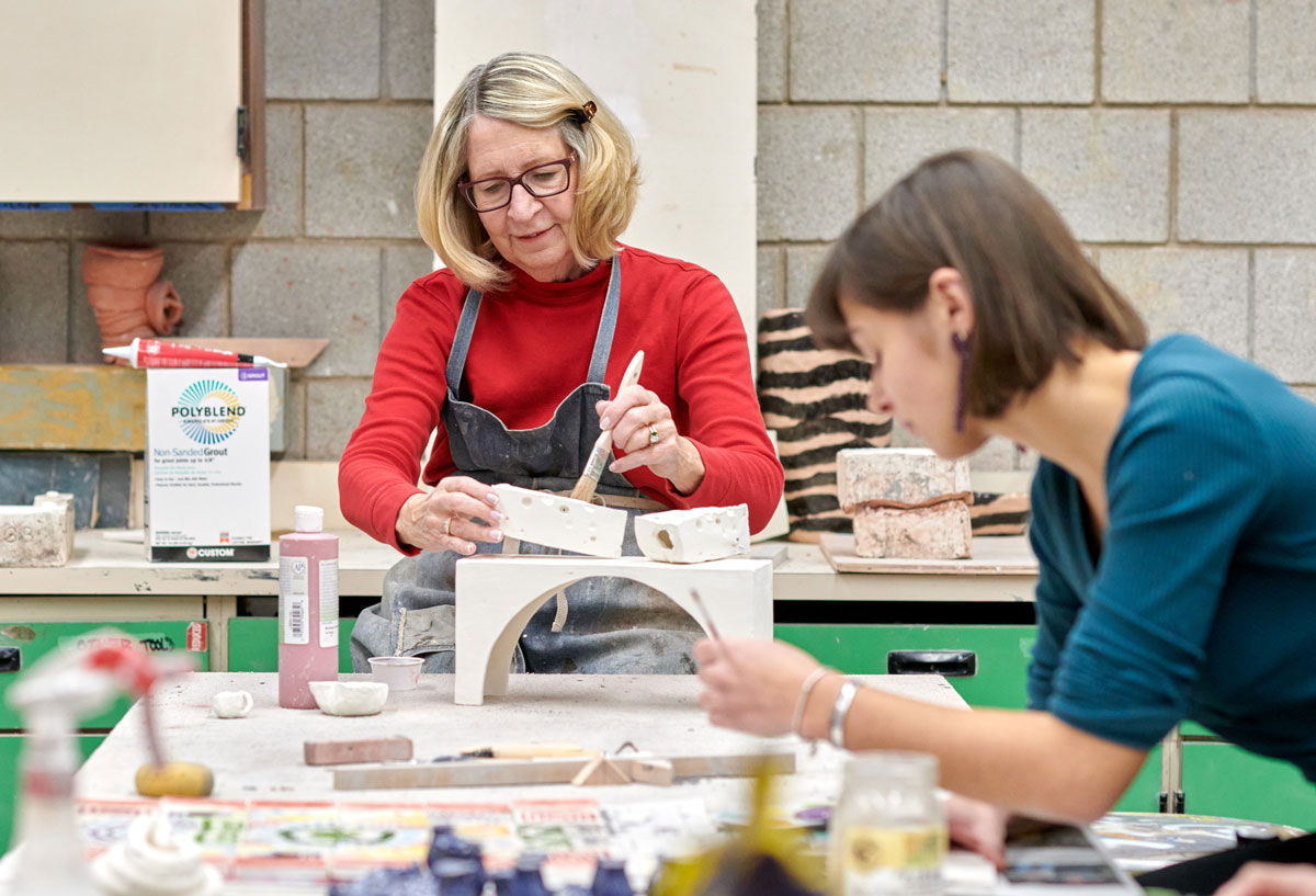 An older woman and younger woman work on craft projects