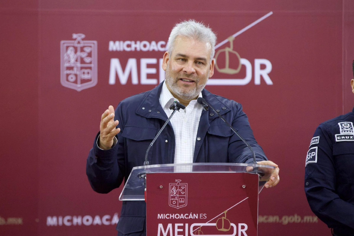 El gobernador Alfredo Ramírez Bedolla gesticulando mientras habla en un pódium oficial con el lema "Michoacán es Mejor" y el escudo del estado de fondo.